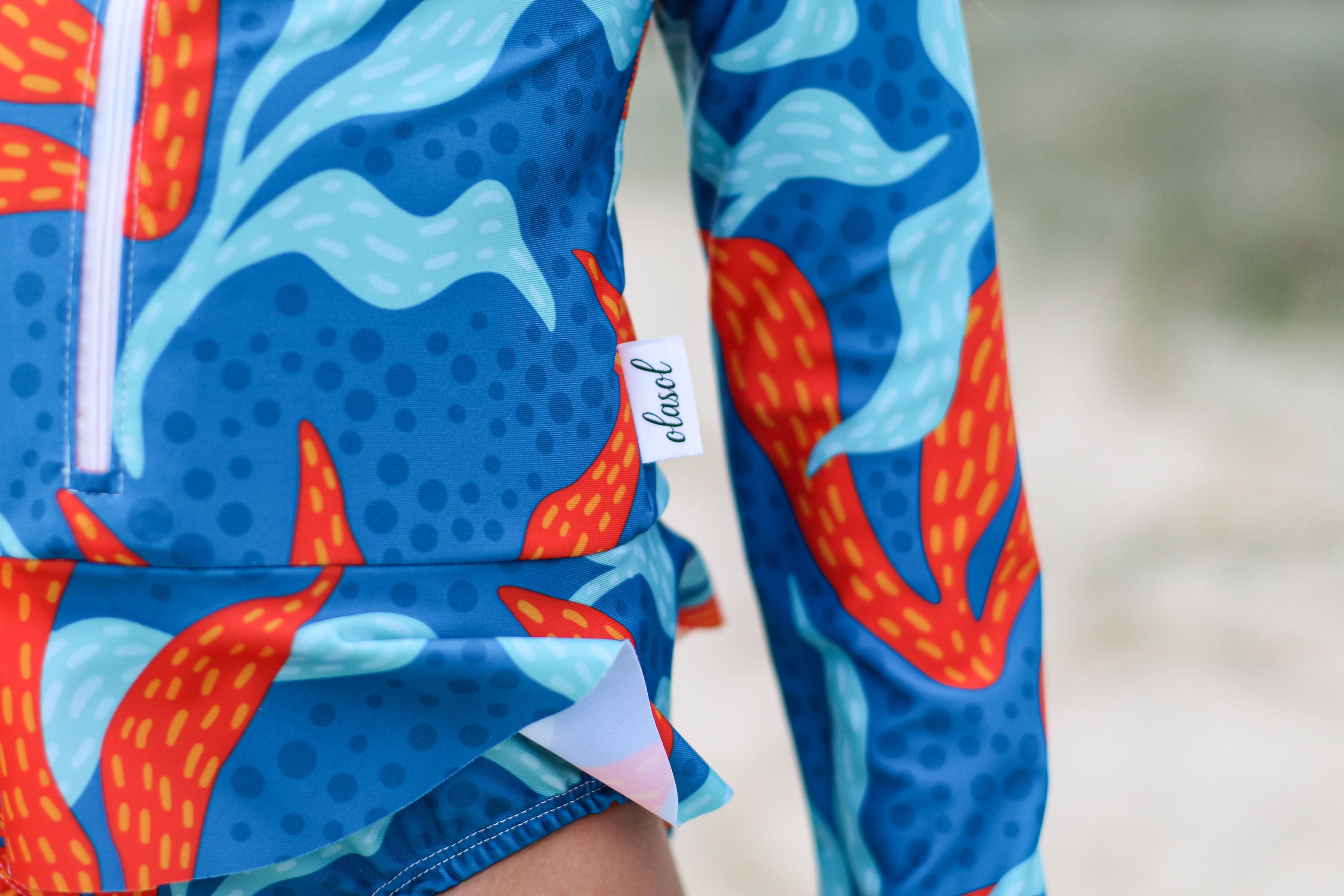 A close up of a girls long sleeved swimsuit in a kelp print.